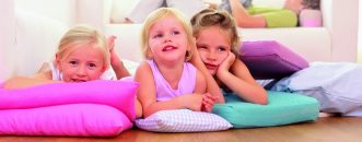 Three sisters lying on cushions, father sleeping on sofa in the back --- Image by © Royalty-Free/Corbis