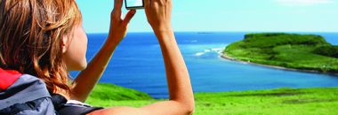 Young woman with backpack taking photo of a great landscape